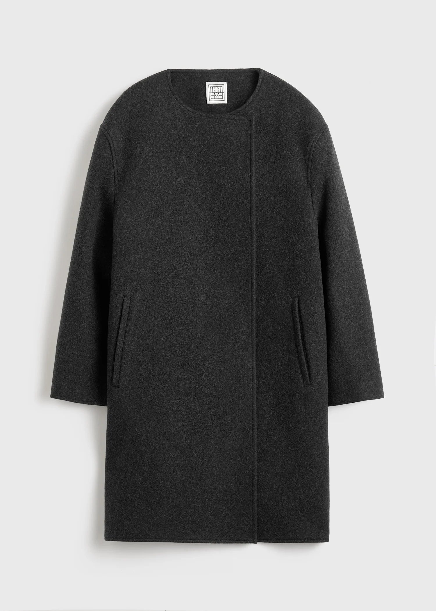 Effortless sophistication meets architectural design in this collarless felt coat by Toteme. Crafted from substantial wool-blend felt, its clean lines and drop shoulders create a modern silhouette that drapes like a protective shell around your frame. The buttonless double-breasted front eliminates fussy closures, while jet pockets offer practical elegance. Partial interior lining and an internal pocket balance minimalist aesthetics with everyday functionality. 