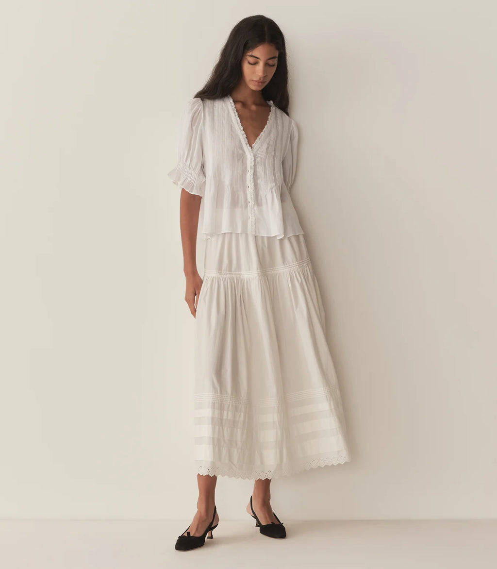 Experience timeless elegance with the Karlie Top, crafted from lightweight ramie for a delicate, airy feel. Its plunging V-neckline framed by soft ruffles and intricate pintuck detailing adds a touch of vintage charm. The starburst button line down the front enhances its refined look, while short puffed sleeves bring a playful silhouette. Perfect for wearing loose or tucked into high-waisted jeans, this versatile top effortlessly elevates any outfit with a graceful Edwardian-inspired style.