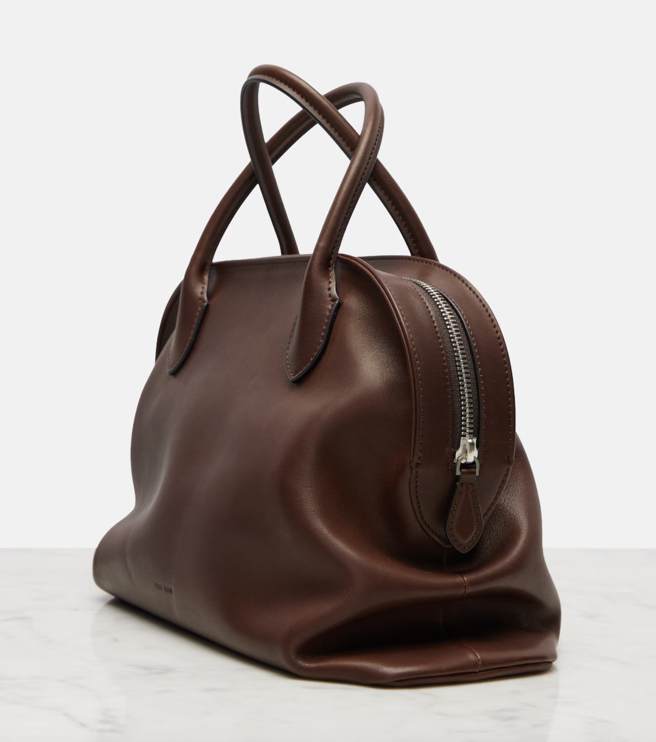 The Agnes tote by The Row combines understated luxury with everyday practicality. Crafted from polished saddle leather, this sophisticated bag features a softly slouched silhouette that moves with you, paired with sturdy tubular handles for effortless carrying. The secure zipper closure keeps your essentials protected while maintaining the bag's refined aesthetic. Perfect for those who appreciate timeless design and quality craftsmanship, the Agnes transitions seamlessly from work to weekend.