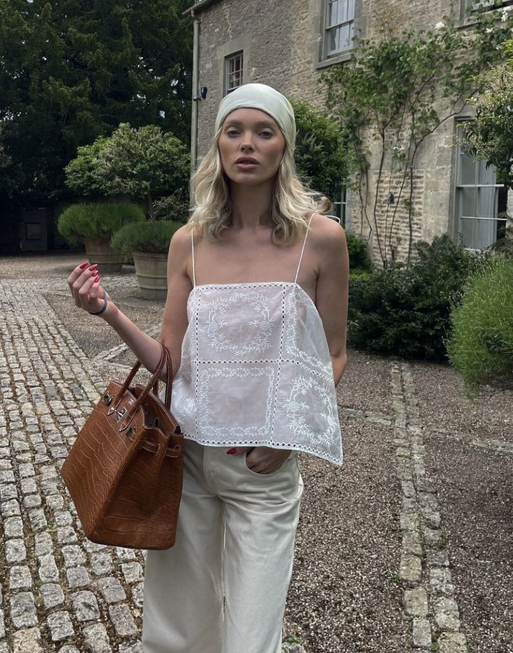 Introducing the Handkerchief Camisole, crafted from luxurious linen and adorned with delicate eyelets and embroidered florals. The shoulder strap tie closures and side slits add a touch of sophistication. Perfect for warm weather, this garment is purposefully sheer, adding an alluring touch. Don't be afraid to let your undergarments peek through. Elevate your wardrobe with this elegant piece.