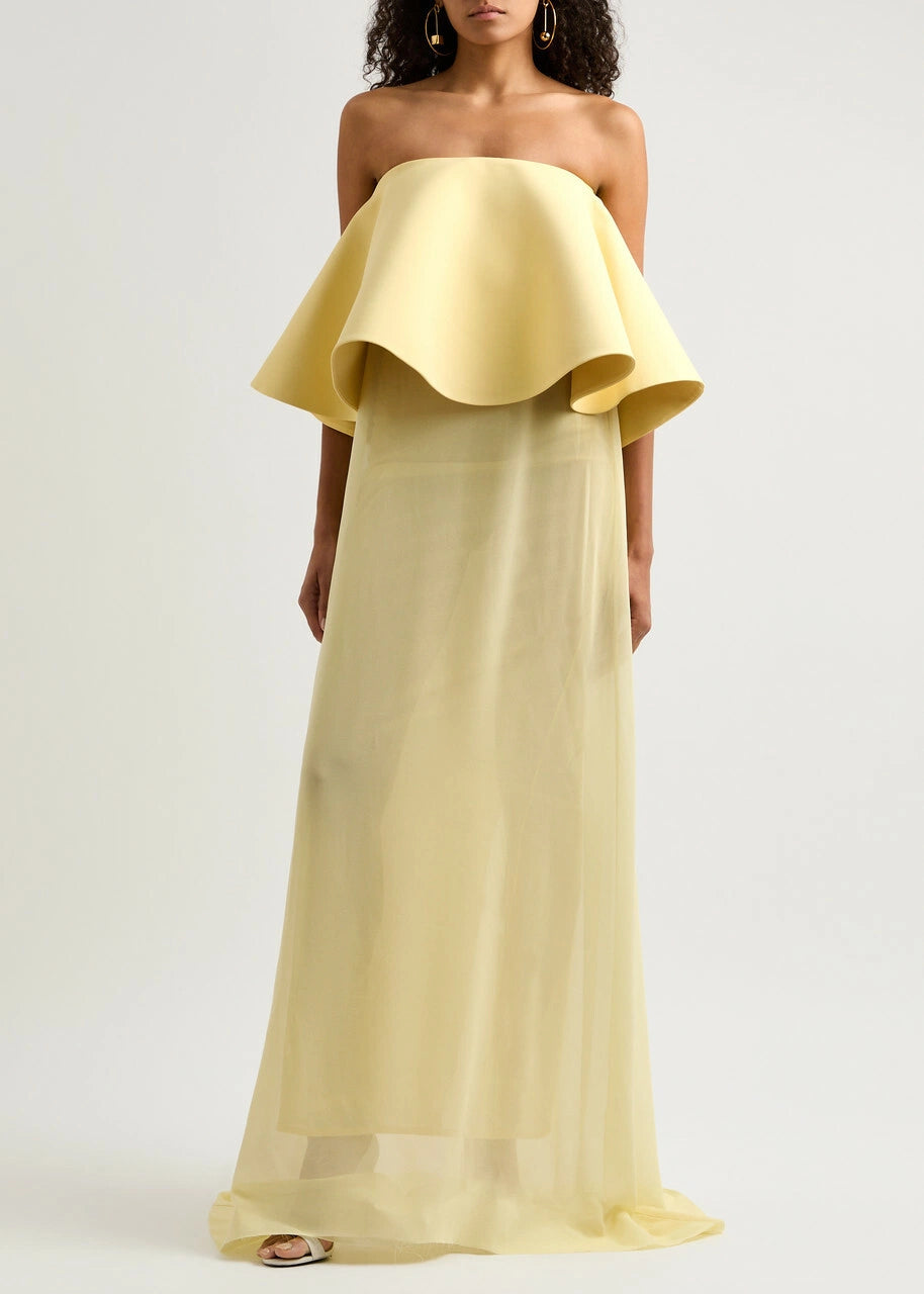 The La Robe Vela Strapless Chiffon Gown in Yellow Light by Jacquemus embodies modern elegance with its flowing, loose silhouette. Designed with a boned bodice for structure and a striking contrasting flared overlay at the bust, this gown offers a sophisticated yet effortless look perfect for making a statement. Its lightweight chiffon fabric drapes beautifully, ensuring comfort and grace for any occasion. Embrace refined style with this standout piece from Jacquemus’s AW24 collection.