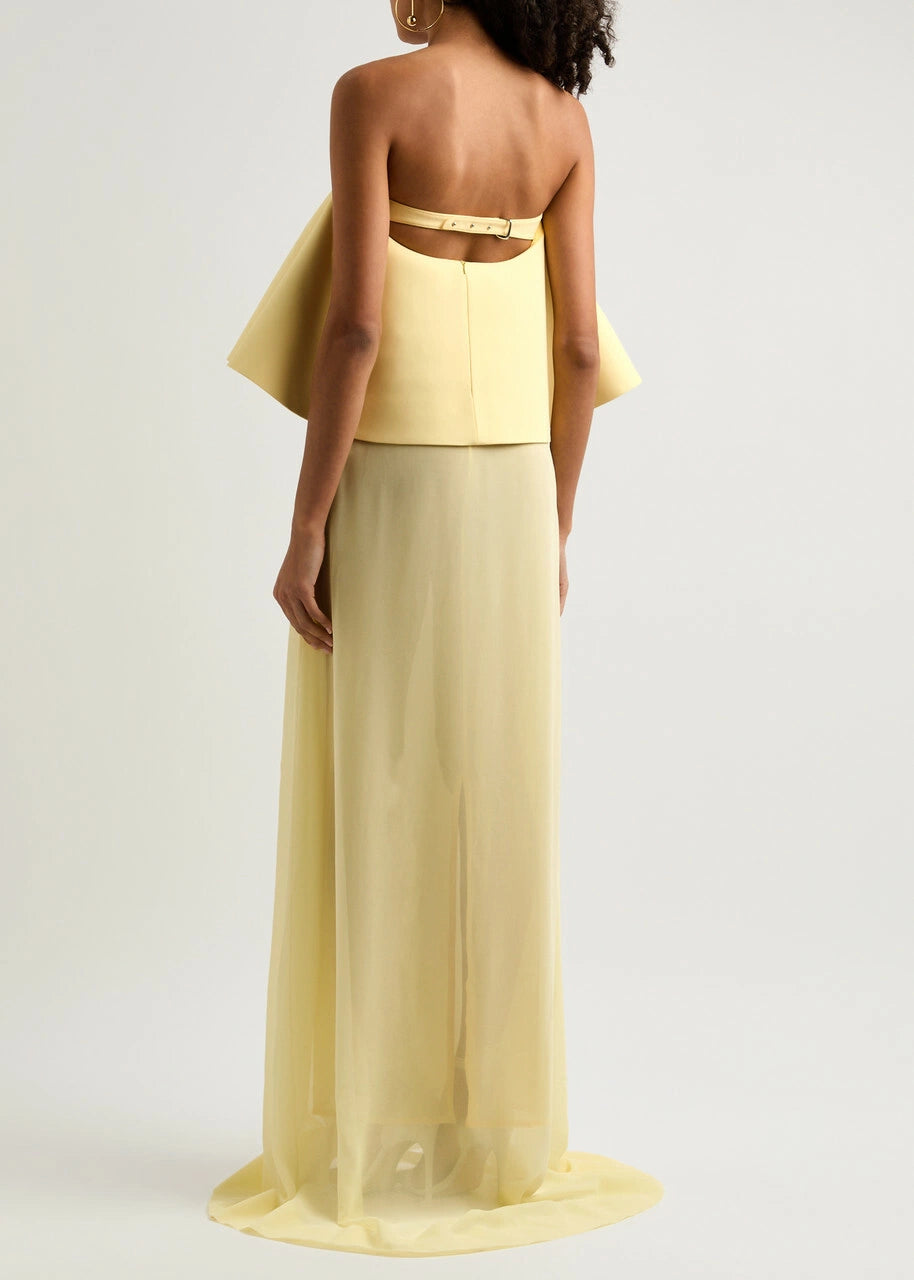 The La Robe Vela Strapless Chiffon Gown in Yellow Light by Jacquemus embodies modern elegance with its flowing, loose silhouette. Designed with a boned bodice for structure and a striking contrasting flared overlay at the bust, this gown offers a sophisticated yet effortless look perfect for making a statement. Its lightweight chiffon fabric drapes beautifully, ensuring comfort and grace for any occasion. Embrace refined style with this standout piece from Jacquemus’s AW24 collection.