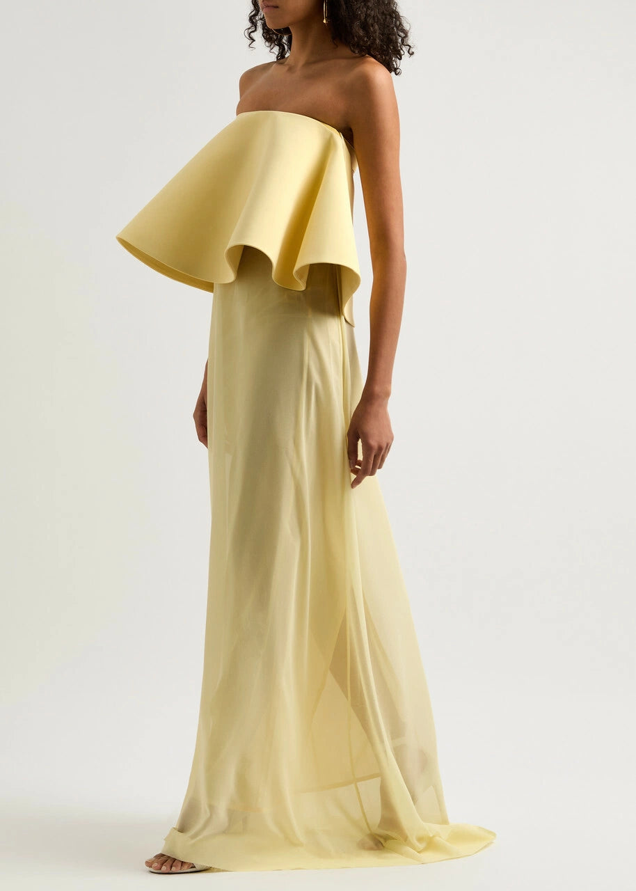 The La Robe Vela Strapless Chiffon Gown in Yellow Light by Jacquemus embodies modern elegance with its flowing, loose silhouette. Designed with a boned bodice for structure and a striking contrasting flared overlay at the bust, this gown offers a sophisticated yet effortless look perfect for making a statement. Its lightweight chiffon fabric drapes beautifully, ensuring comfort and grace for any occasion. Embrace refined style with this standout piece from Jacquemus’s AW24 collection.
