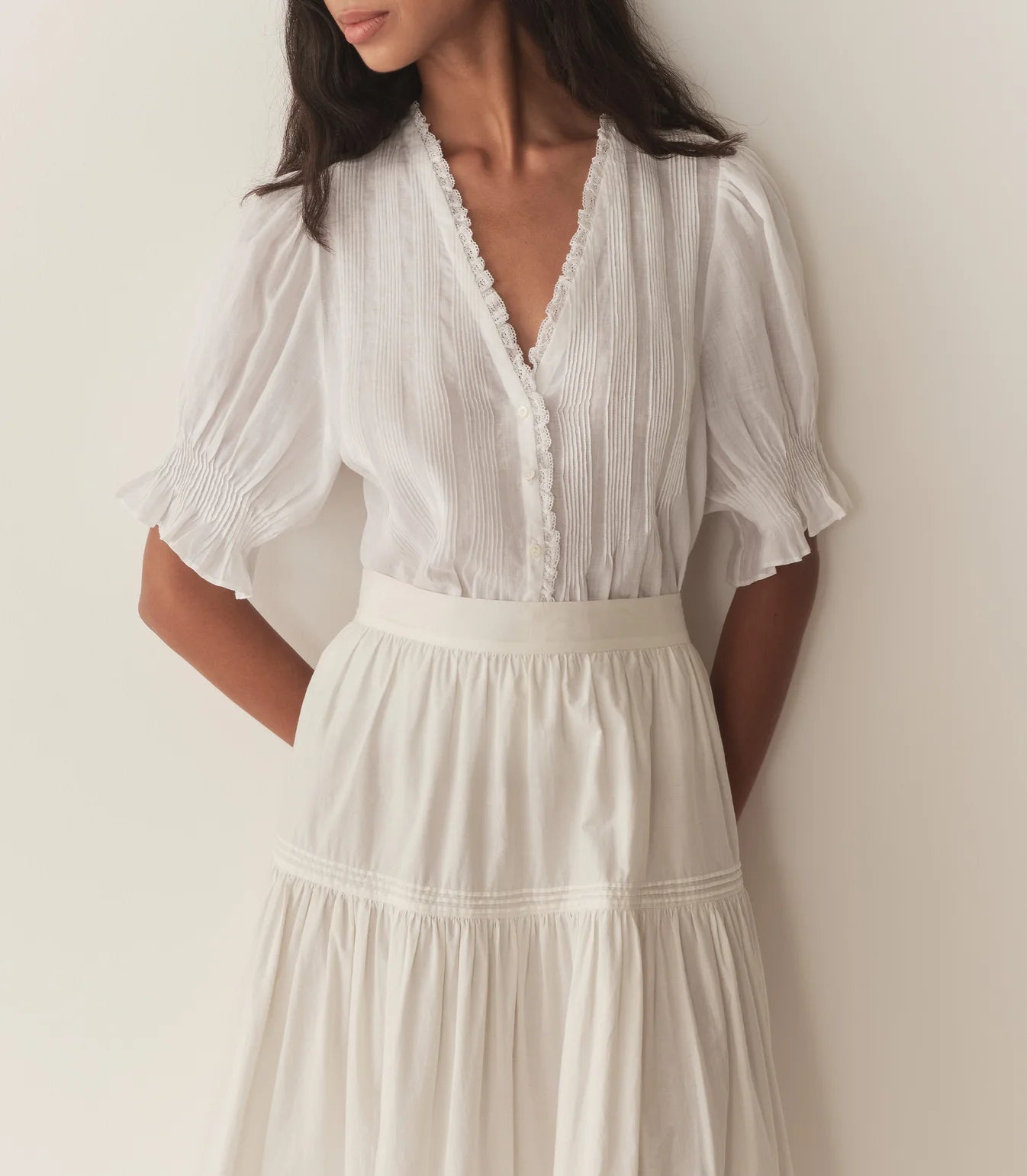 Experience timeless elegance with the Karlie Top, crafted from lightweight ramie for a delicate, airy feel. Its plunging V-neckline framed by soft ruffles and intricate pintuck detailing adds a touch of vintage charm. The starburst button line down the front enhances its refined look, while short puffed sleeves bring a playful silhouette. Perfect for wearing loose or tucked into high-waisted jeans, this versatile top effortlessly elevates any outfit with a graceful Edwardian-inspired style.