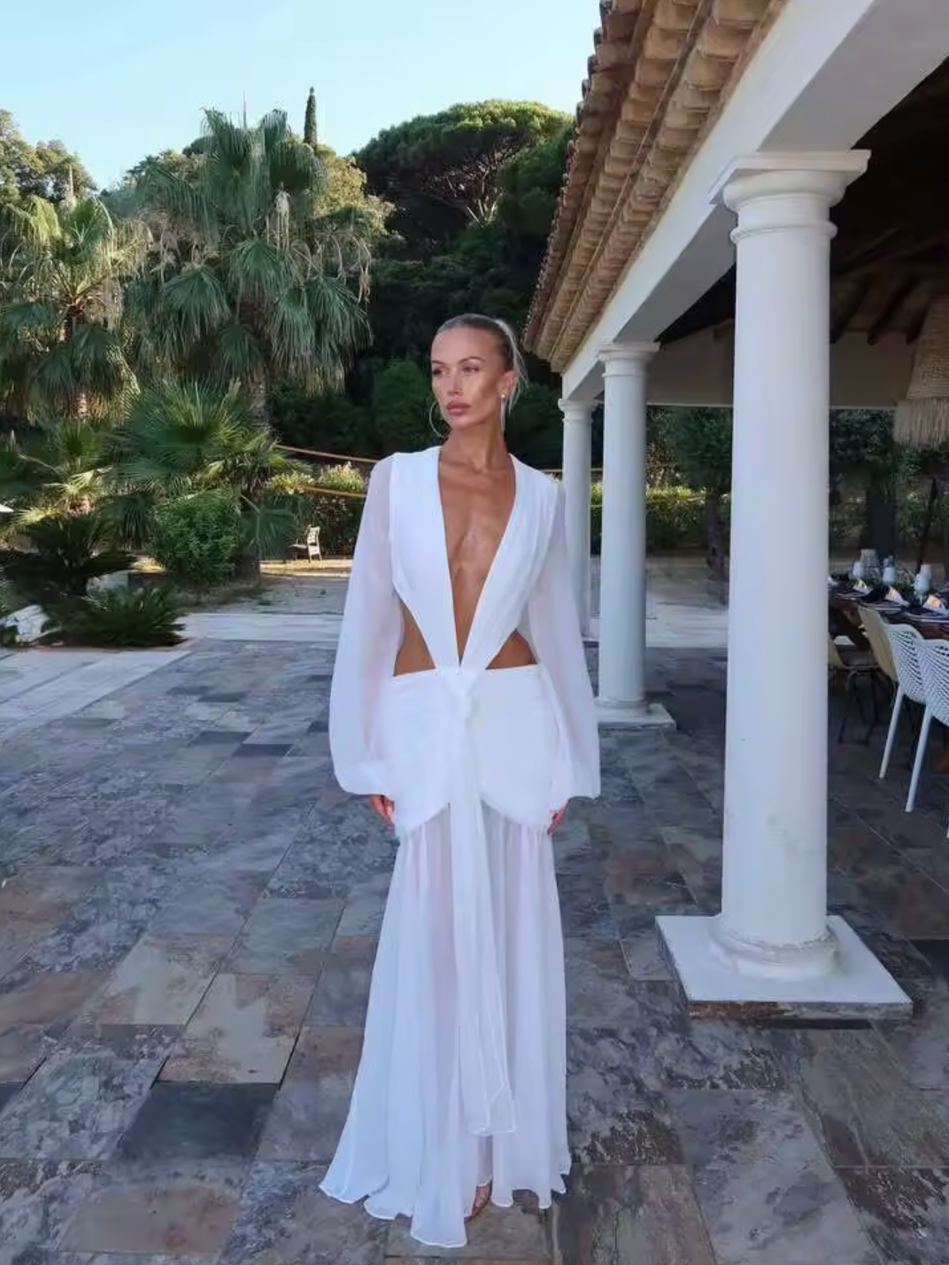 The Andrina Maxi Dress is a stunning statement piece that combines romance with modern elegance. Crafted from delicate chiffon, this maxi features long, sheer blouson sleeves and a daring deep plunge neckline that exudes confidence. The open lace-up back with adjustable ties allows you to customize your fit while showcasing an alluring silhouette. 