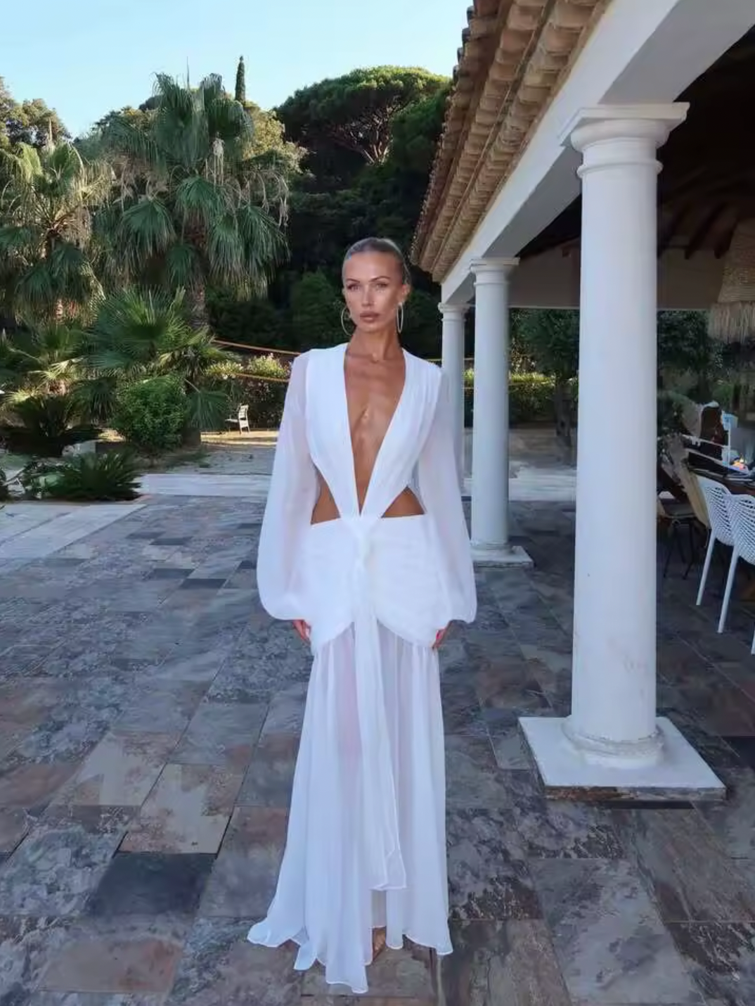 The Andrina Maxi Dress is a stunning statement piece that combines romance with modern elegance. Crafted from delicate chiffon, this maxi features long, sheer blouson sleeves and a daring deep plunge neckline that exudes confidence. The open lace-up back with adjustable ties allows you to customize your fit while showcasing an alluring silhouette. 