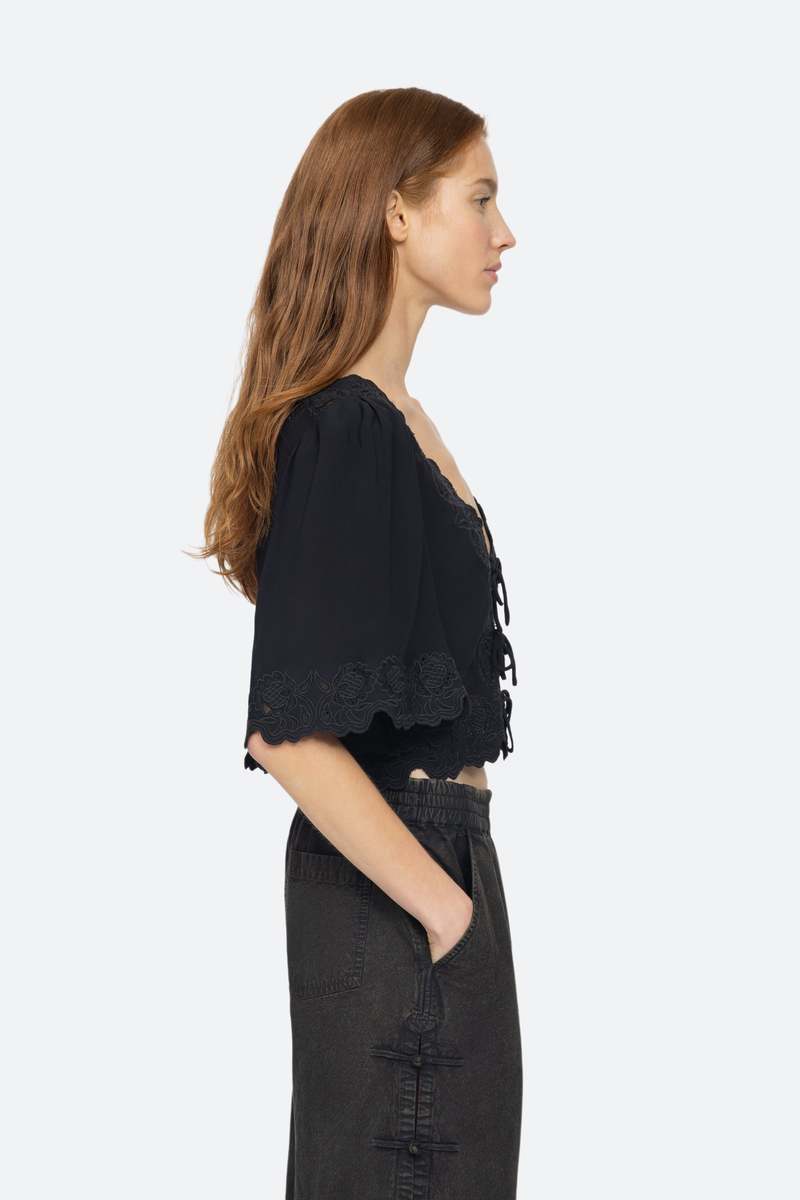 Elevate your wardrobe with the effortlessly elegant Baylin Top in Black by SEA. Delicate lace detailing and front tie closures exude sophistication and charm, while the flowy short sleeves add a touch of femininity. Luxurious and versatile, this top is a must-have for any occasion.