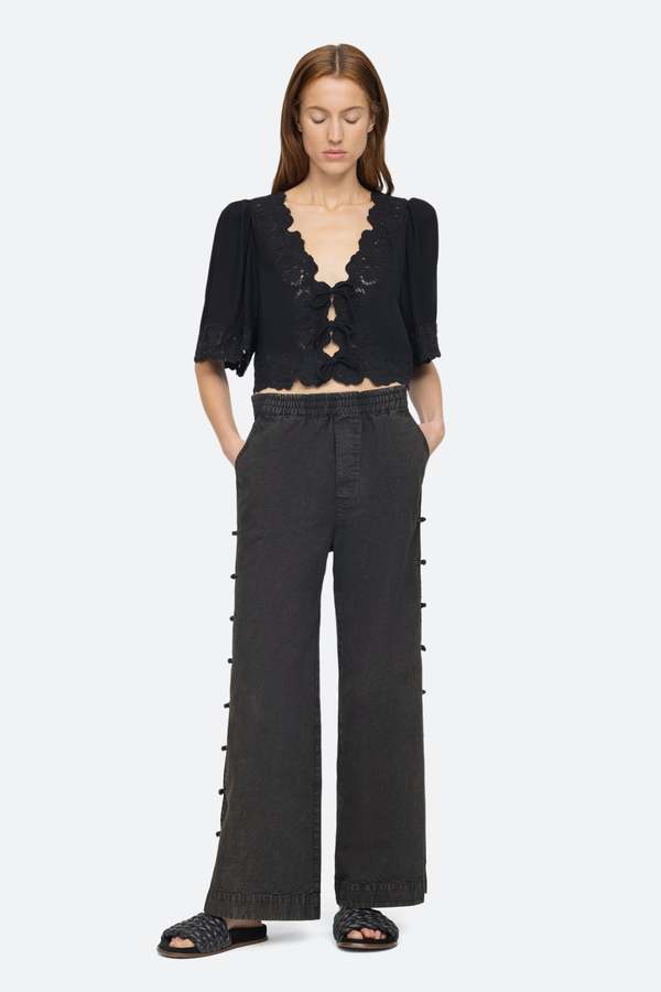 Elevate your wardrobe with the effortlessly elegant Baylin Top in Black by SEA. Delicate lace detailing and front tie closures exude sophistication and charm, while the flowy short sleeves add a touch of femininity. Luxurious and versatile, this top is a must-have for any occasion.