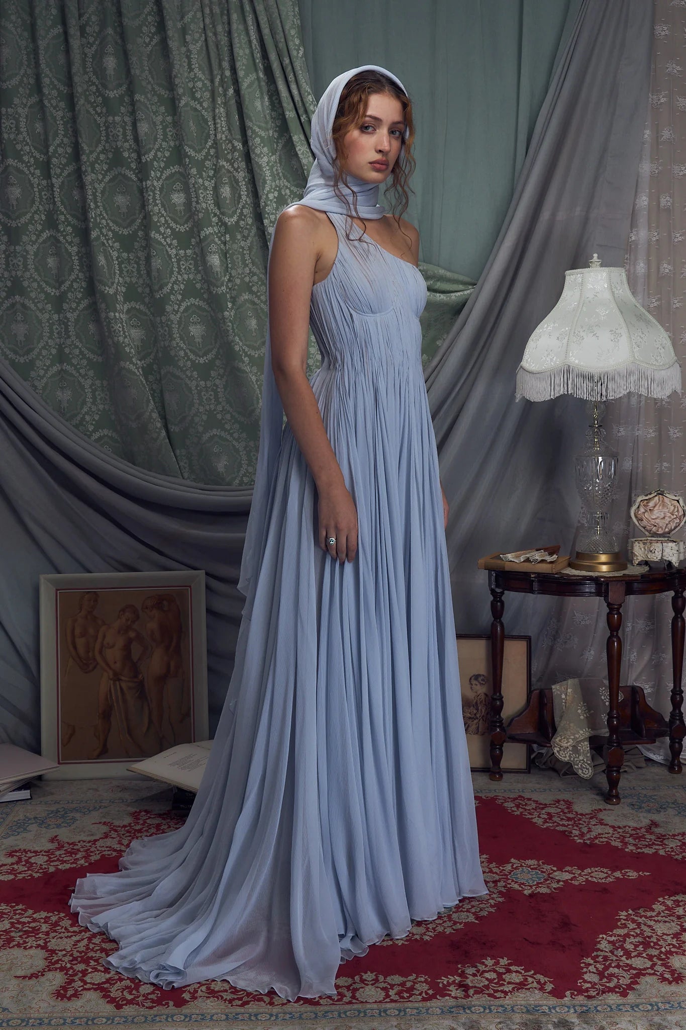 Embrace elegance with the Hellenistic Gown in Ciel, designed to captivate with a one-shoulder silhouette crafted from delicate crinkle chiffon. Its underwire cups and power mesh lining provide comfortable support and a flawless fit, while the attached scarf adds a touch of grace. The high slit offers sophisticated allure, and the invisible zipper with hook and eye closure ensures a seamless look. Perfect for making a memorable entrance, this gown combines style and confidence effortlessly.