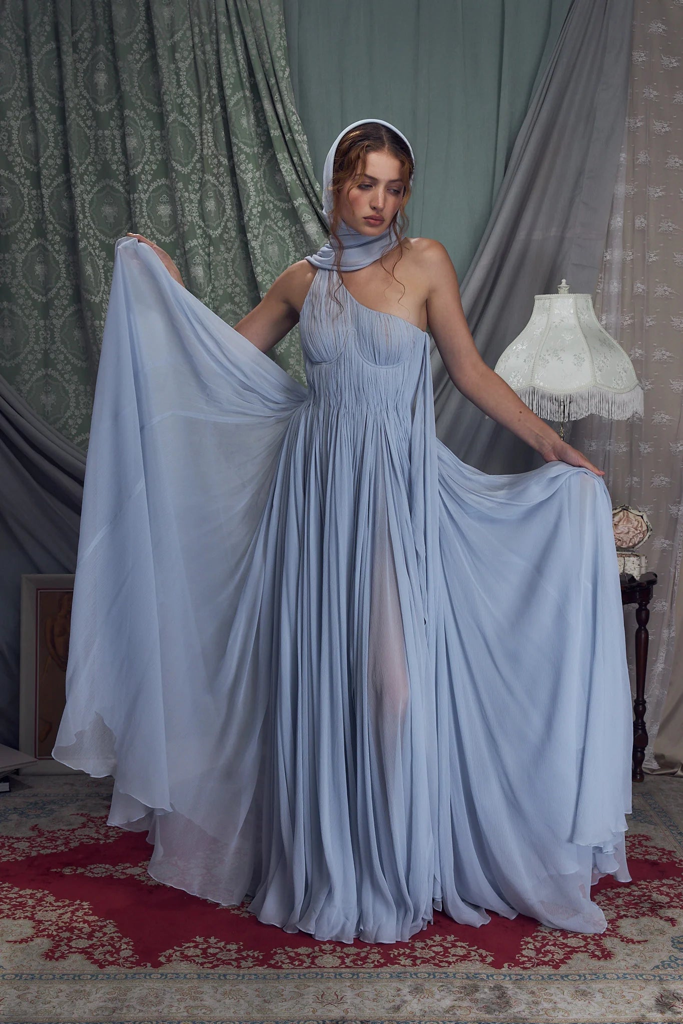 Embrace elegance with the Hellenistic Gown in Ciel, designed to captivate with a one-shoulder silhouette crafted from delicate crinkle chiffon. Its underwire cups and power mesh lining provide comfortable support and a flawless fit, while the attached scarf adds a touch of grace. The high slit offers sophisticated allure, and the invisible zipper with hook and eye closure ensures a seamless look. Perfect for making a memorable entrance, this gown combines style and confidence effortlessly.