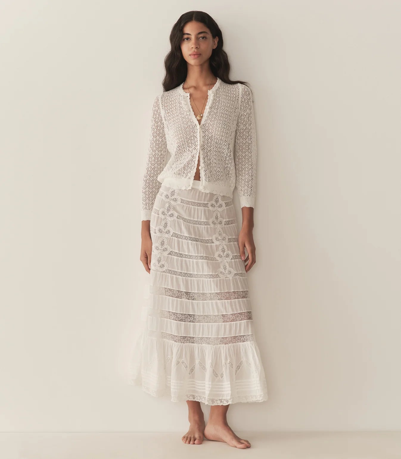 The Diane Cardigan by Doen brings timeless elegance to your everyday wardrobe. This sophisticated piece features a delicate pointelle design reminiscent of Victorian bobbin lace, crafted from a breathable viscose blend that drapes beautifully without feeling heavy. The classic crew neckline and bracelet-length sleeves offer versatile styling options, while charming crocheted buttons and scallop-edge ribbing at the neckline, cuffs, and hem add refined detail. 