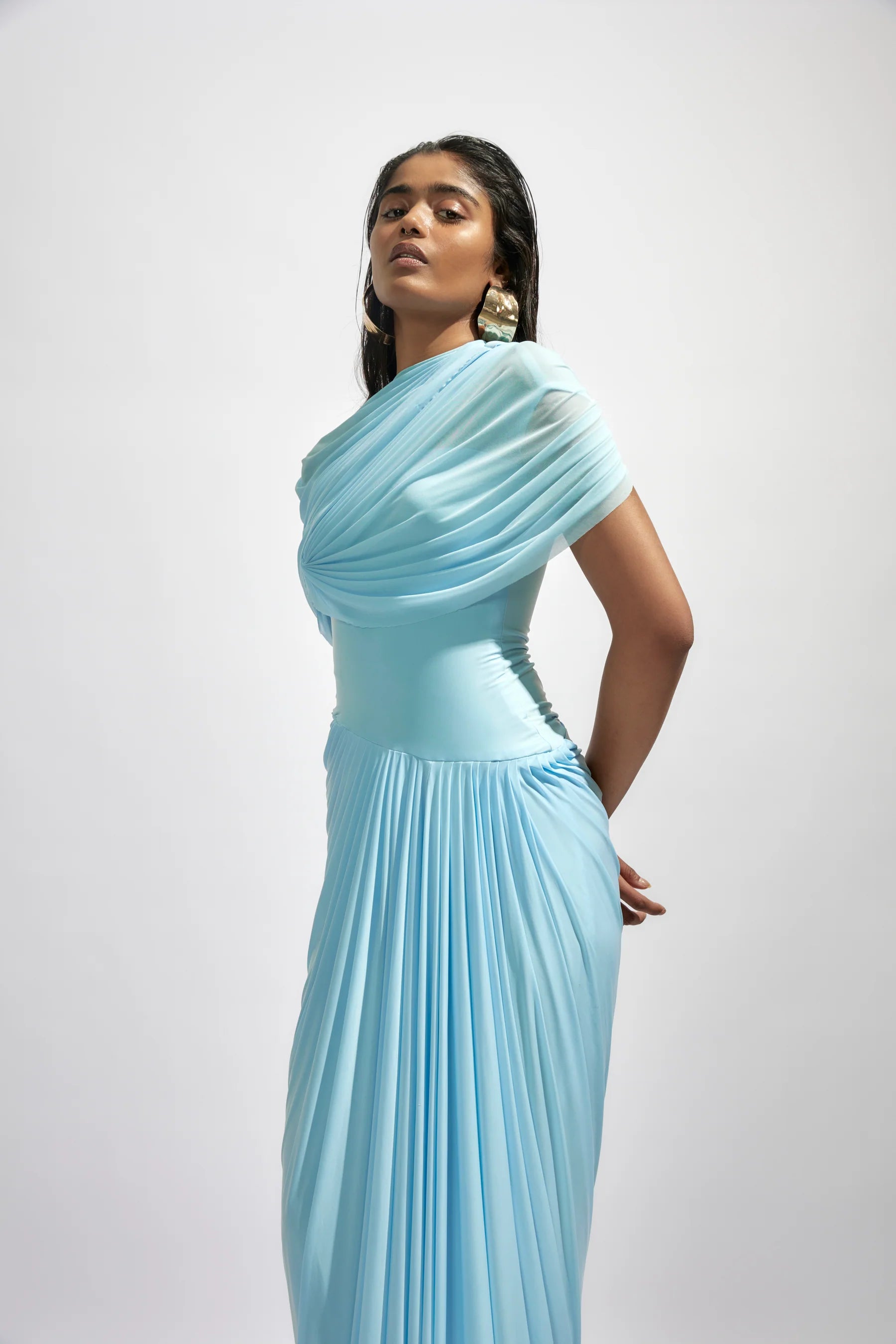 The Jasmine Dress features a fully draped design enhanced by delicate pleated details, adding texture and graceful movement. Its elegant silhouette and refined pleats bring timeless sophistication, making it an ideal choice for special occasions where you want to stand out with confidence and style.