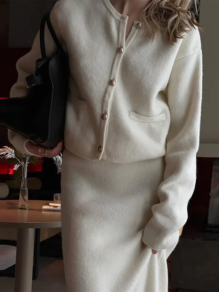 Upgrade your wardrobe with Ensemble Dora: an elegant and stylish 2 piece set featuring a Golden O-neck cardigan and white knit midi skirt. Perfect for any occasion, this single-breasted ensemble will add a touch of elegance to your outfit while keeping you cozy and comfortable.