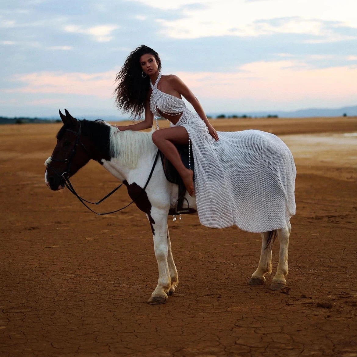 Discover elegance and sophistication in our Gown Amanda. This halter gown features stunning pearls and intricate beading, adding a touch of glamour to your evening look. The sleeveless design and beautiful sweep train make this a perfect choice for proms and special events.