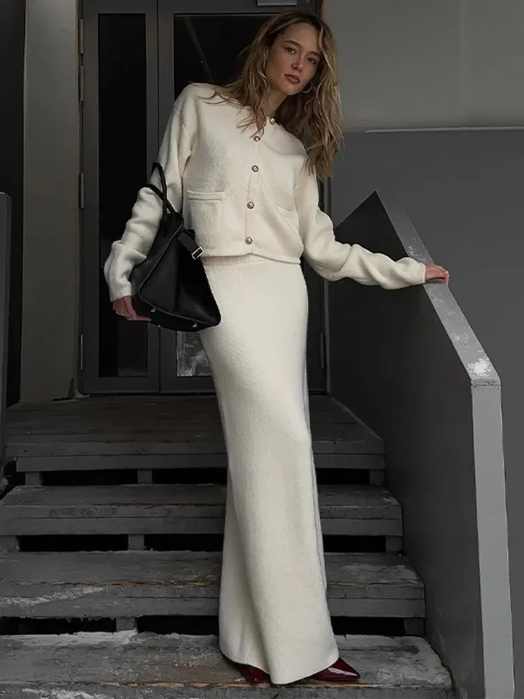 Upgrade your wardrobe with Ensemble Dora: an elegant and stylish 2 piece set featuring a Golden O-neck cardigan and white knit midi skirt. Perfect for any occasion, this single-breasted ensemble will add a touch of elegance to your outfit while keeping you cozy and comfortable.
