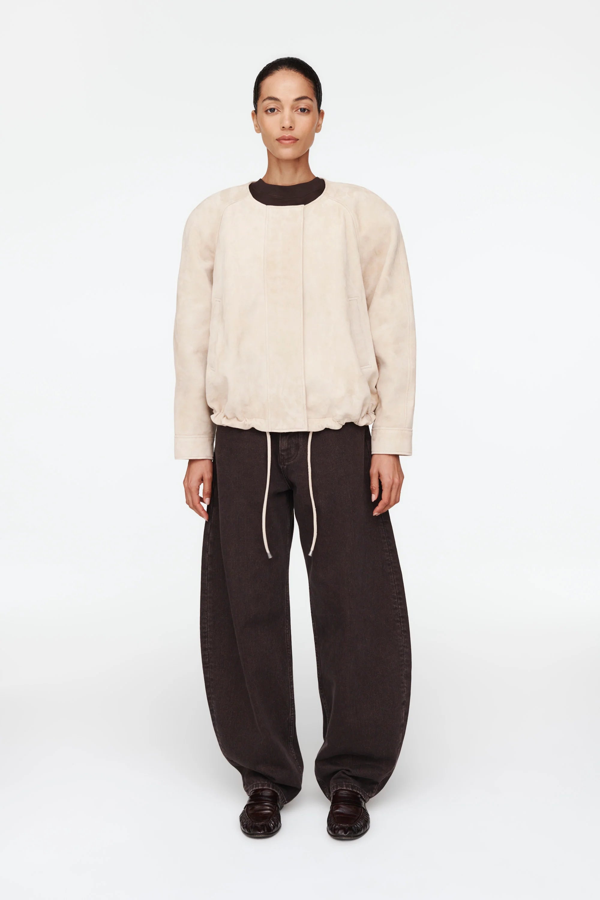 The Suki Suede Jacket redefines the classic aviator style with a sleek, collarless design for modern comfort. Its adjustable hem with drawstrings lets you customize your fit, making it perfect for daily wear. Crafted to be your go-to layer, this jacket combines style and functionality so seamlessly, you'll never want to take it off. Elevate your wardrobe with this versatile essential.