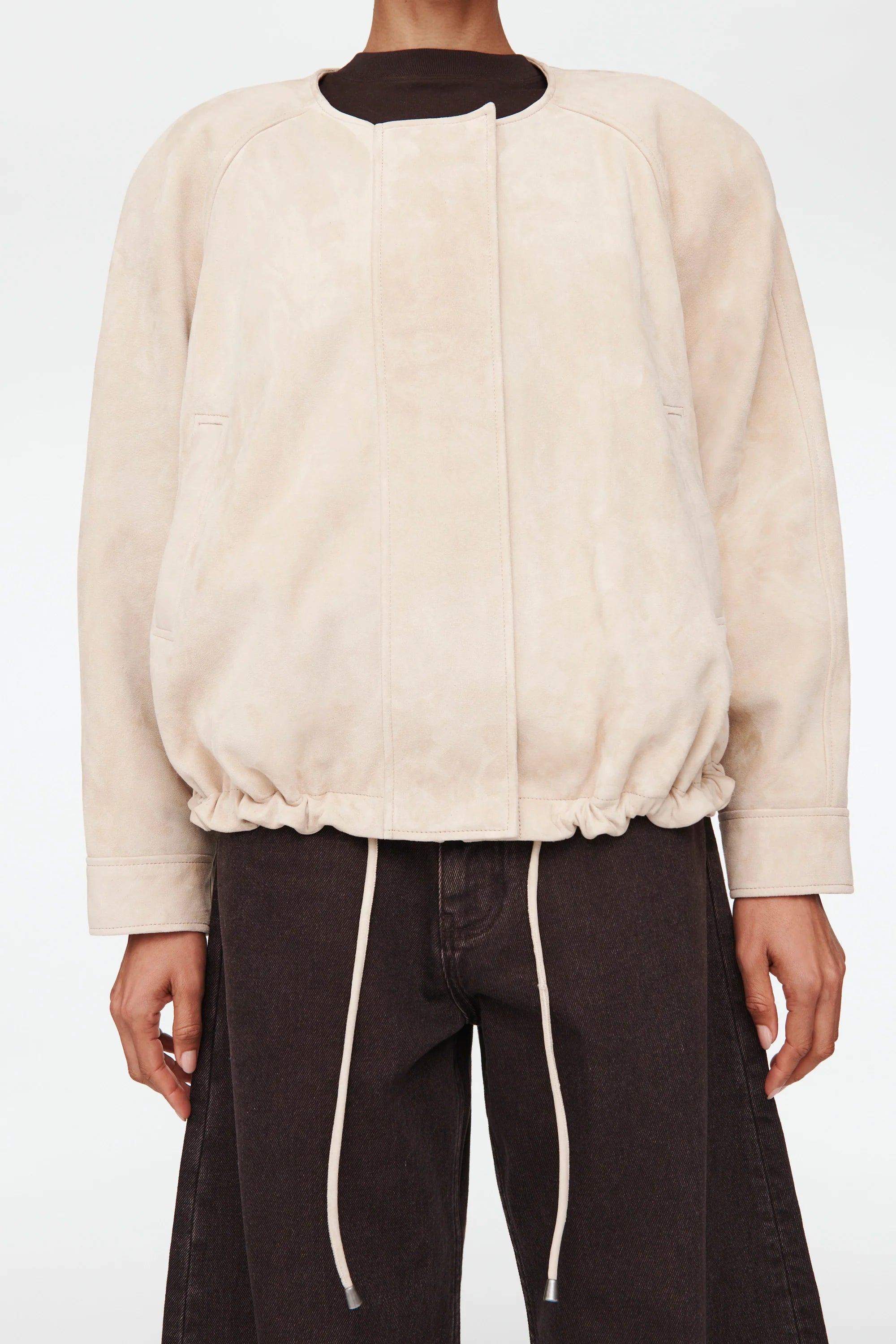 The Suki Suede Jacket redefines the classic aviator style with a sleek, collarless design for modern comfort. Its adjustable hem with drawstrings lets you customize your fit, making it perfect for daily wear. Crafted to be your go-to layer, this jacket combines style and functionality so seamlessly, you'll never want to take it off. Elevate your wardrobe with this versatile essential.