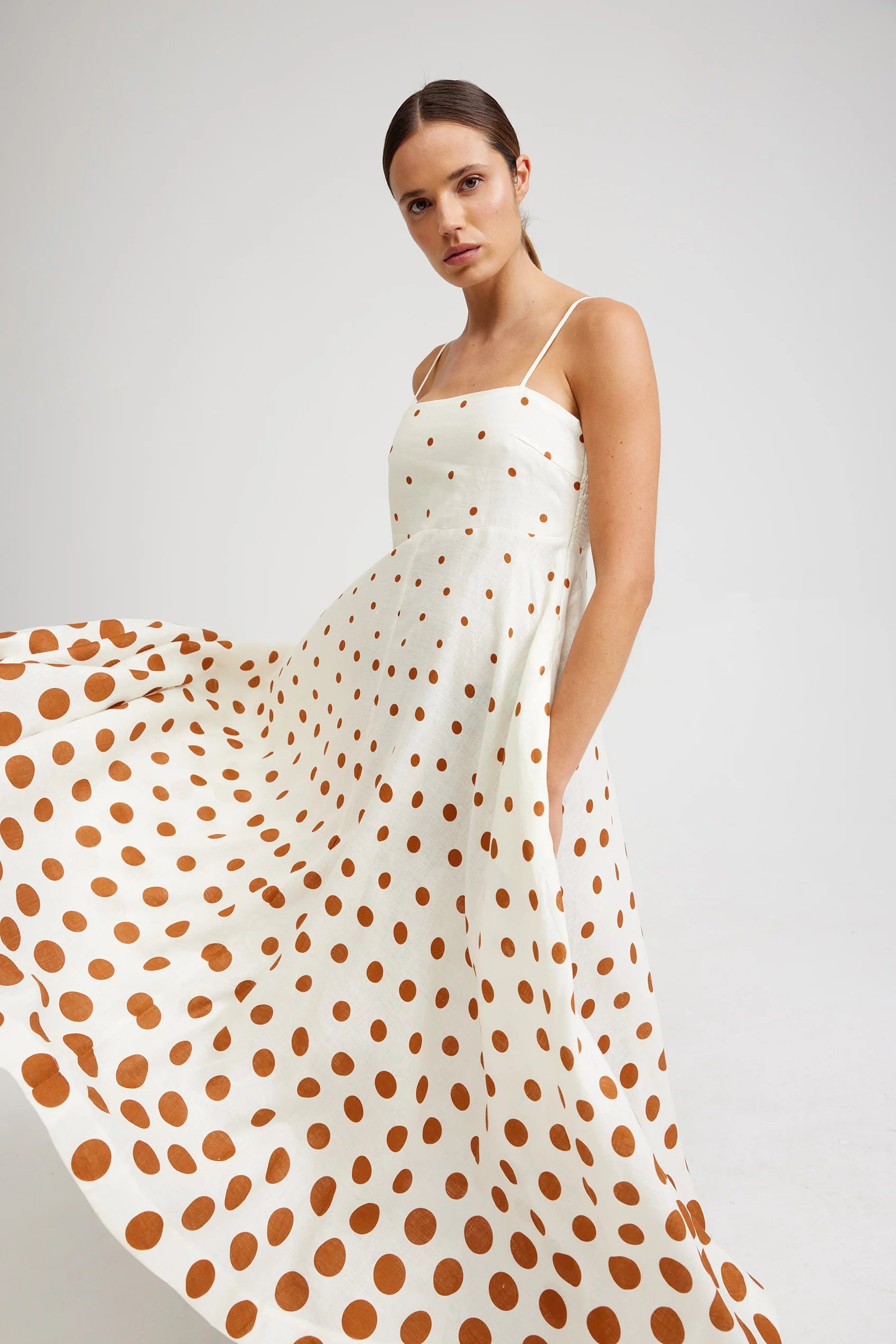 The Rue Dress in Cigar Dot by Aston Studio offers a refined yet relaxed fit, designed to flatter every figure. Adjustable shoulder straps ensure a perfect fit, while the full skirt adds graceful movement and timeless elegance. Featuring our exclusive dot pattern on both front and back, this dress makes a striking and unique statement wherever you go. Embrace effortless sophistication with the Rue Dress.
