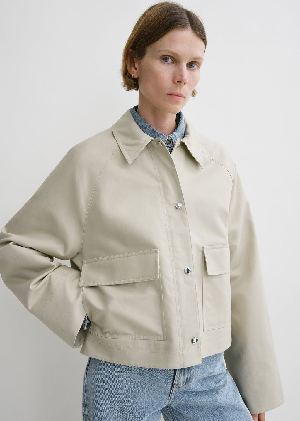 This cropped cotton jacket by Toteme in a warm sand hue features a wide, boxy silhouette with roomy raglan sleeves for a modern, relaxed fit. Crafted from compact organic cotton, it offers durability and comfort. Functional details like a silver-tone zipper, snap buttons, and utilitarian flap pockets add practicality without compromising style. Fully lined in a matching tone, it pairs effortlessly with jeans and pumps, making it the perfect choice for casual coffee outings with a chic edge.