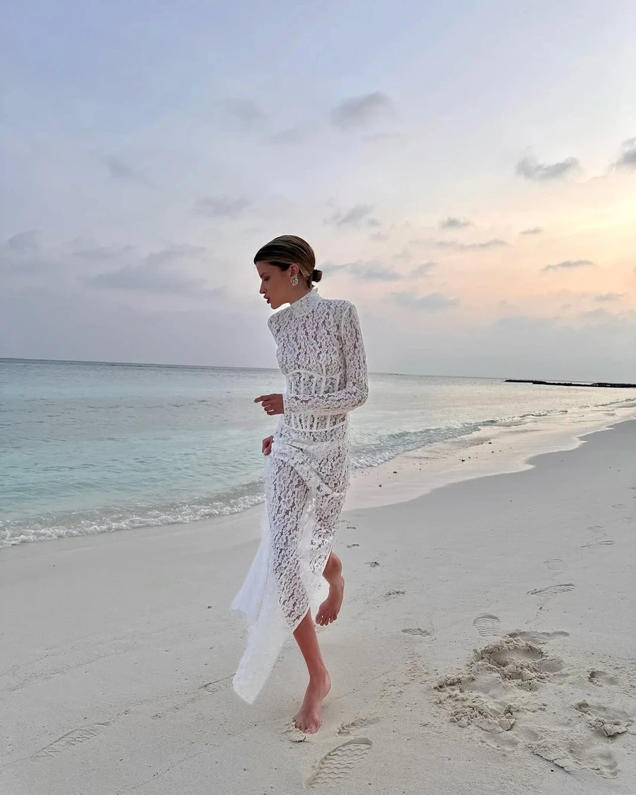 The Isadora gown by The New Arrivals Ilkyaz Ozel epitomizes refined elegance with its pristine white silhouette and architectural design. Featuring a structured boned bodice that sculpts the figure with precision, this statement piece showcases a sophisticated mock neck and innovative cuff zips for versatile styling. The concealed rear zip fastening ensures a seamless, polished finish. Perfect for those who appreciate couture-inspired details and timeless sophistication.