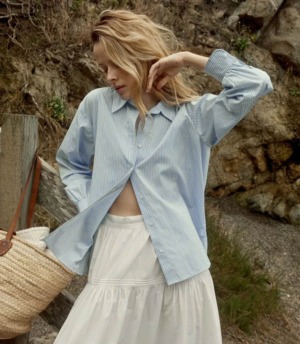 Elevate your wardrobe with the Hava Top in Santorini Stripe by Doen. Made from luxurious Italian cotton, this button-down features a sophisticated Santorini Stripe pattern and mother-of-pearl buttons. The embroidered and shirring details add unique flair to its tailored silhouette, perfect for both casual and polished looks. Versatile and elegant, it's a must-have for any fashion-forward individual.