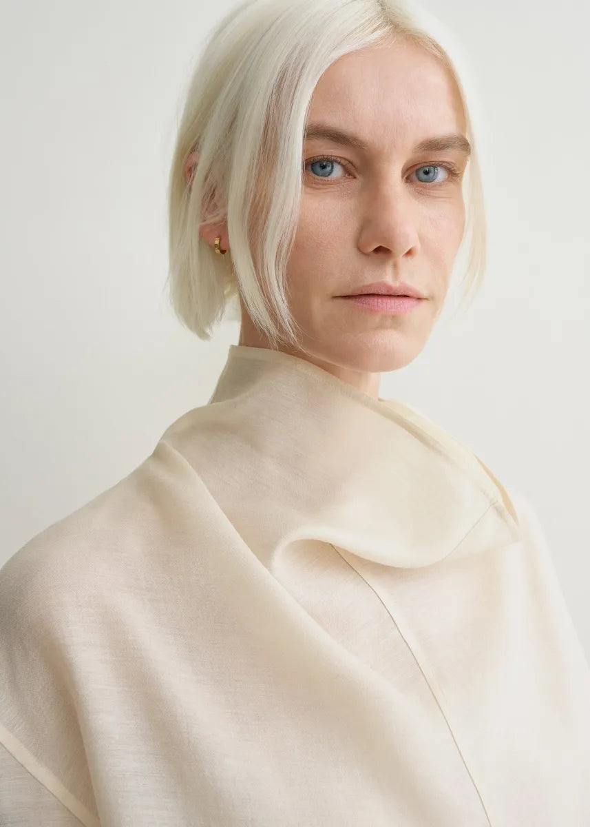 Elevate your wardrobe with this oversized funnel-neck organza blouse by Toteme, designed for effortless sophistication. The lightweight, semi-sheer fabric creates a delicate layering effect when paired with the included cami top. Its roomy fit and elegant neckline bring both comfort and style, making it ideal for pairing with tailored trousers for a polished daytime look. Perfect for those seeking a chic, versatile piece that enhances any outfit with a graceful touch.