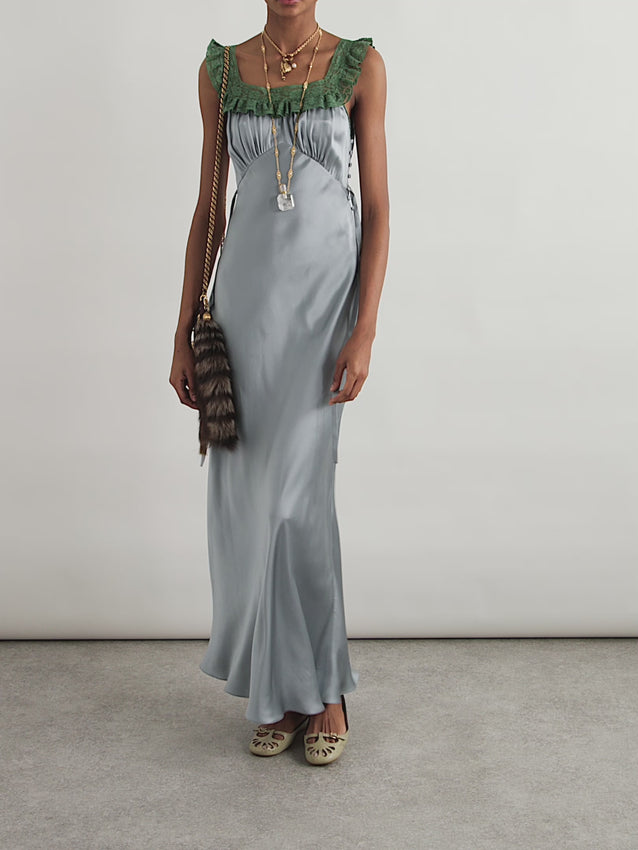 Embrace understated elegance with this exquisite silk-satin gown, inspired by Chloé's Fall '25 collection. Crafted from luxurious liquid-like fabric, the dress skims the silhouette with refined bias cutting that celebrates feminine form. A striking square neckline is adorned with emerald lacework, while delicate side ties and covered buttons add architectural detail. Perfect for evening occasions where timeless sophistication speaks louder than trends.