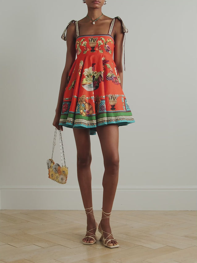 Elevate your warm-weather wardrobe with the Rocco printed linen mini dress by Alemais, a vibrant piece that captures effortless elegance. Featuring a cheerful fruit-print design in rich orange tones, this dress combines playful style with refined details. Adjustable tie straps offer a customizable fit, while the gathered skirt creates flattering movement and dimension. Finished with contrasting brown and teal ribbon trim, this mini dress transitions seamlessly from casual daytime looks to evening occasions.