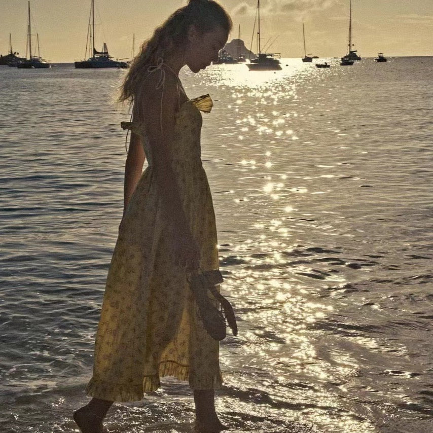 Indulge in the elegance of the Wendelin Midi Dress by Dôen. This beautiful cotton dress features a charming yellow, brown, and cream floral pattern, along with a flattering v waist and adjustable straps for a perfect fit. The delicate ruffle adds a playful touch to this sophisticated and exclusive sundress.