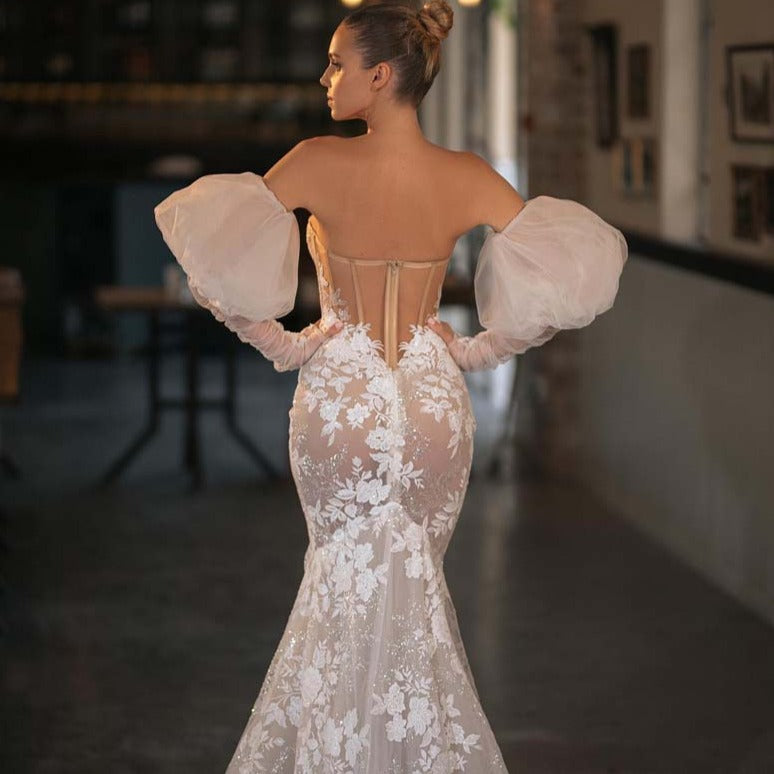 Indulge in the enchanting elegance of the Robe Magda. This stunning dress boasts intricate lace and embroidered flowers adorned with sparkling crystal beading. Its detachable off-the-shoulder puff tulle sleeves add a touch of versatility, while the iconic Berta Bow Belt adds a touch of luxury. Perfect for any special occasion.