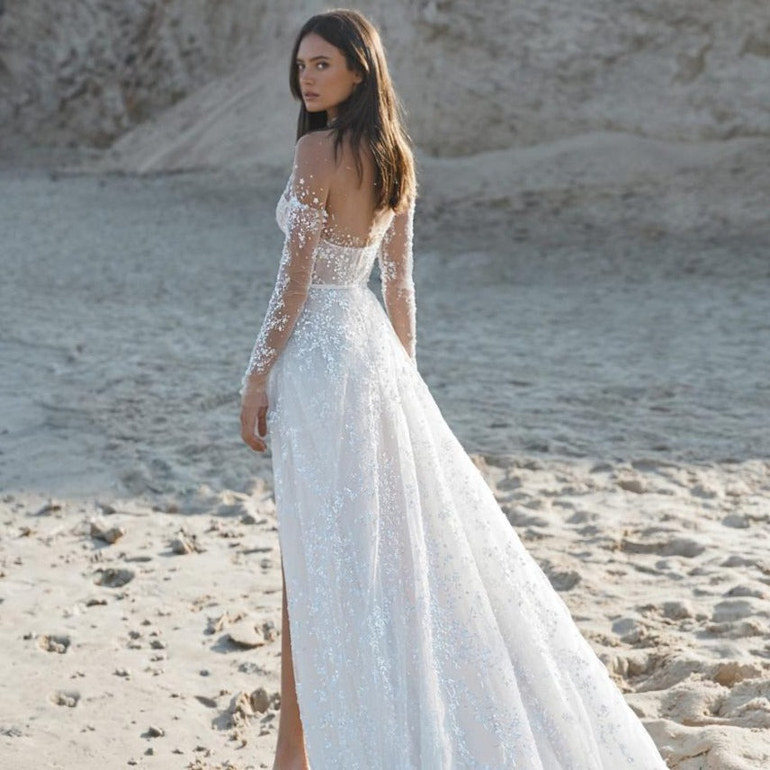 Experience the epitome of elegance with our Robe Rosinne. This stunning bridal beach gown exudes luxurious sophistication, making you feel like a true goddess on your special day. With its beautiful design and high-quality materials, this robe is sure to make you the center of attention as you walk down the aisle or stroll along the beach. Elevate your wedding experience with the Robe Rosinne.